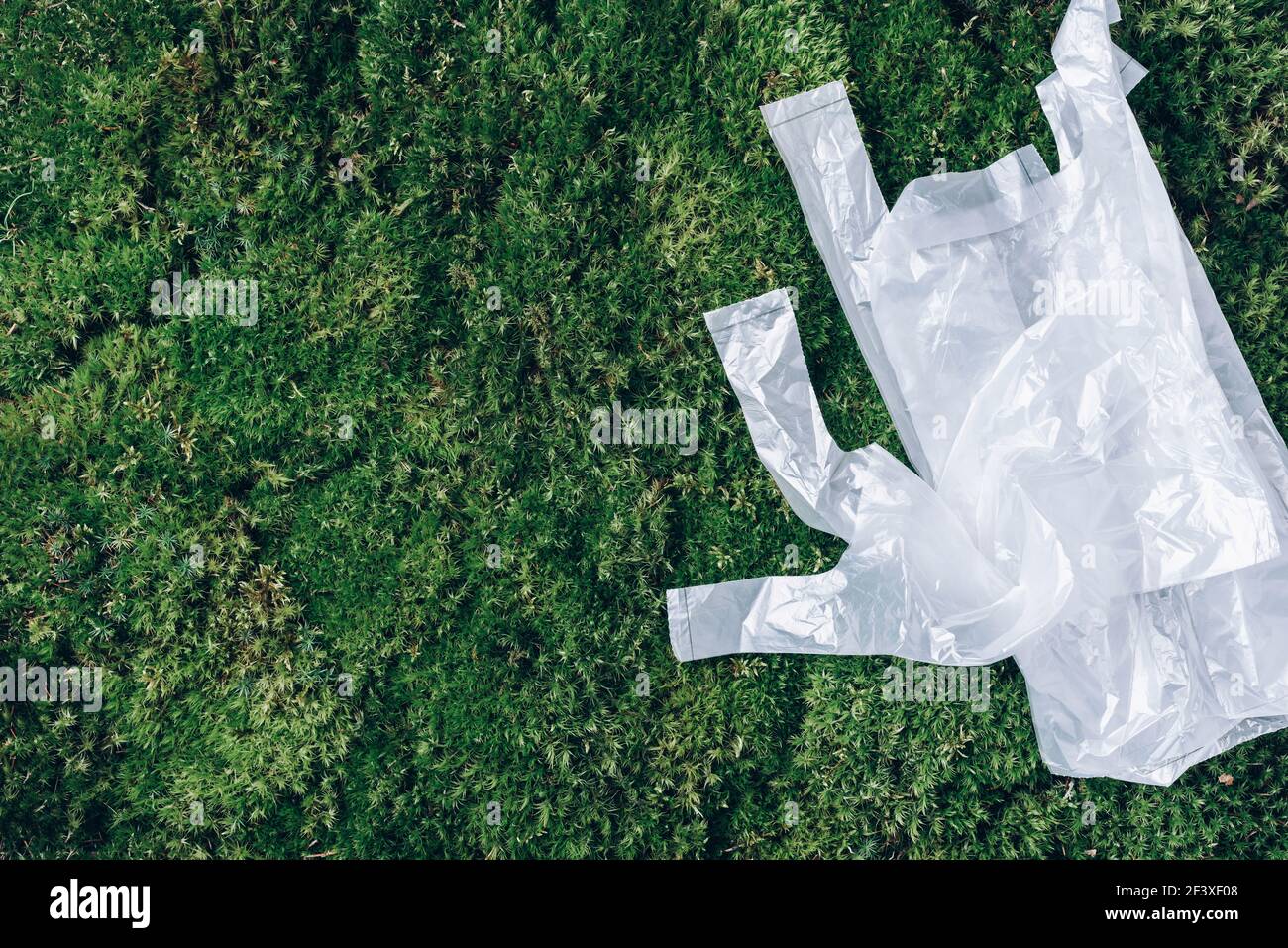 Pollution problem concept. Disposable plastic bags on green moss, grass background. Top view. Copy space. Environmental pollution problem. Garbage Stock Photo