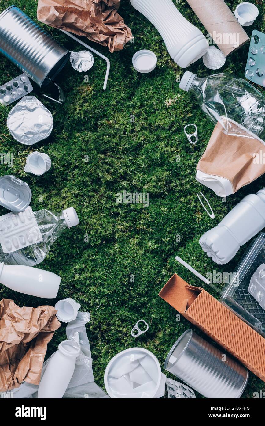 Food plastic packaging, trash on green moss background after picnic in