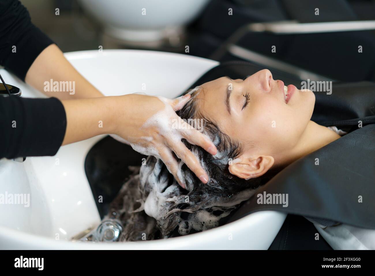 hairdresser is applying shampoo and massaging hair of a customer. Woman