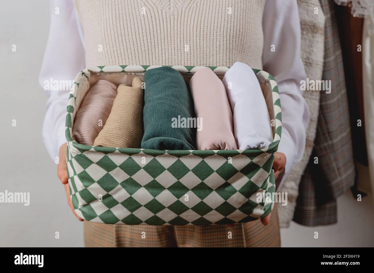 Vertical storage of clothes in a container. In the hands of a woman