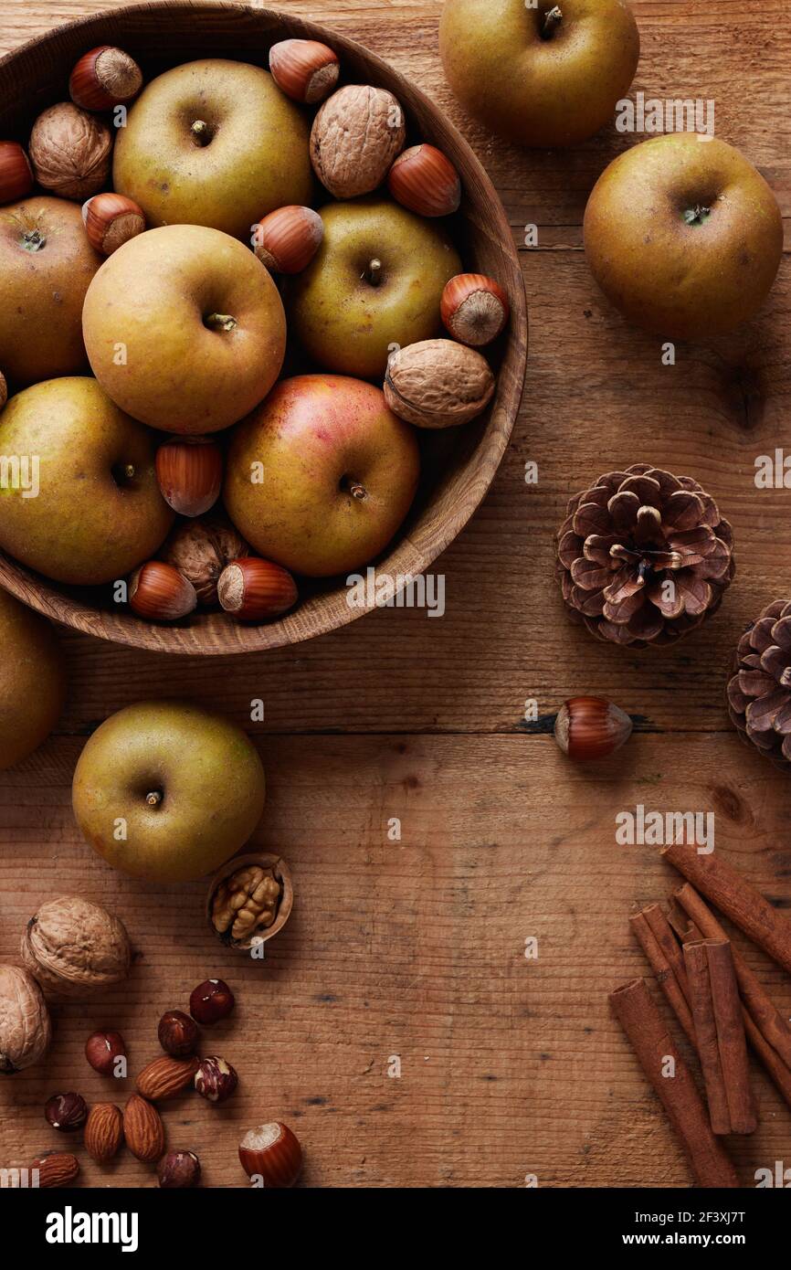 Autumn apples with nuts and cinnamon sticks on table, top view. Heirloom reinette apples. Stock Photo