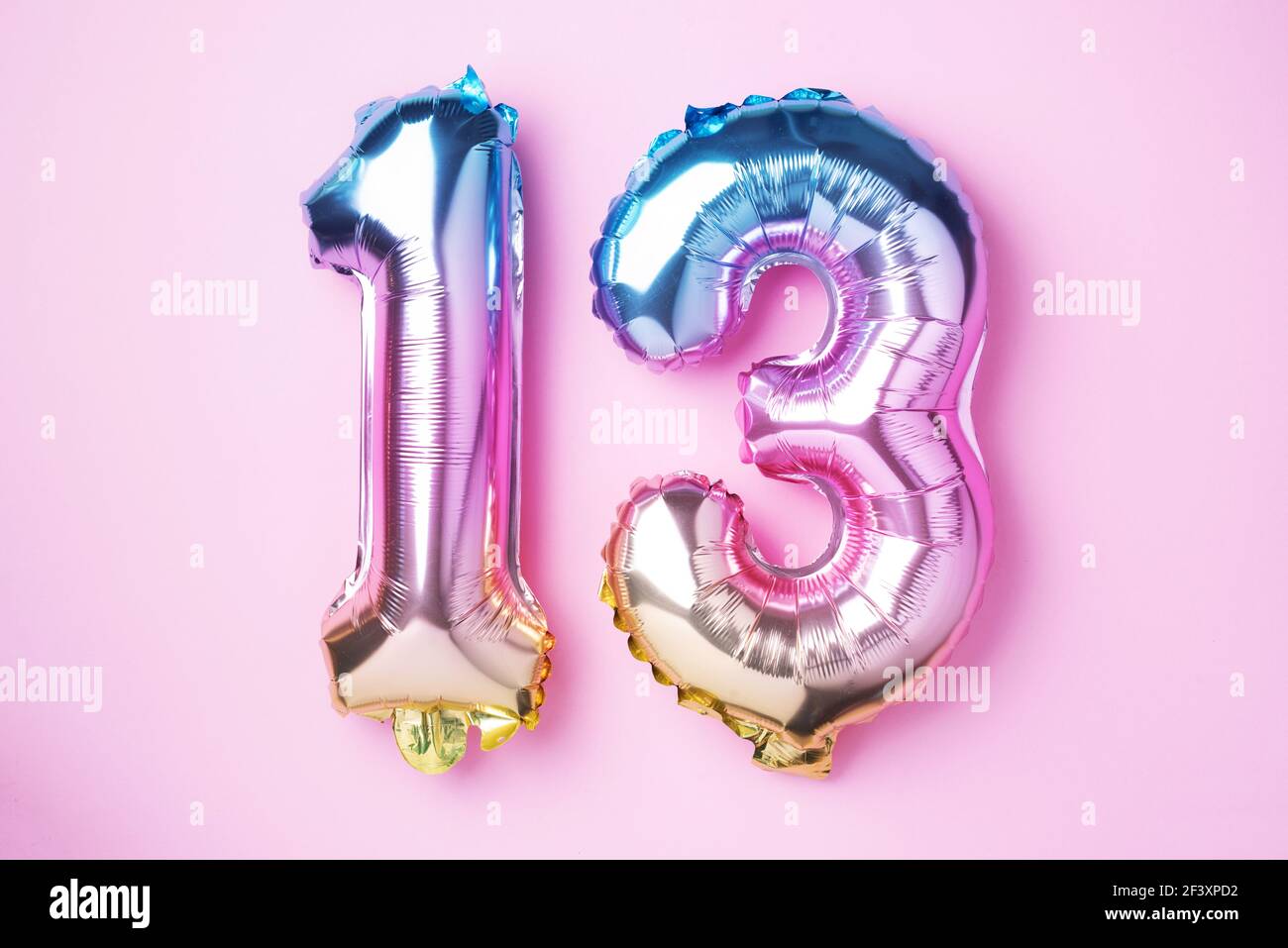 Creative layout. Rainbow foil balloon number, digit thirteen. Birthday greeting card with inscription 13. Anniversary concept. Top view. Stylish Stock Photo