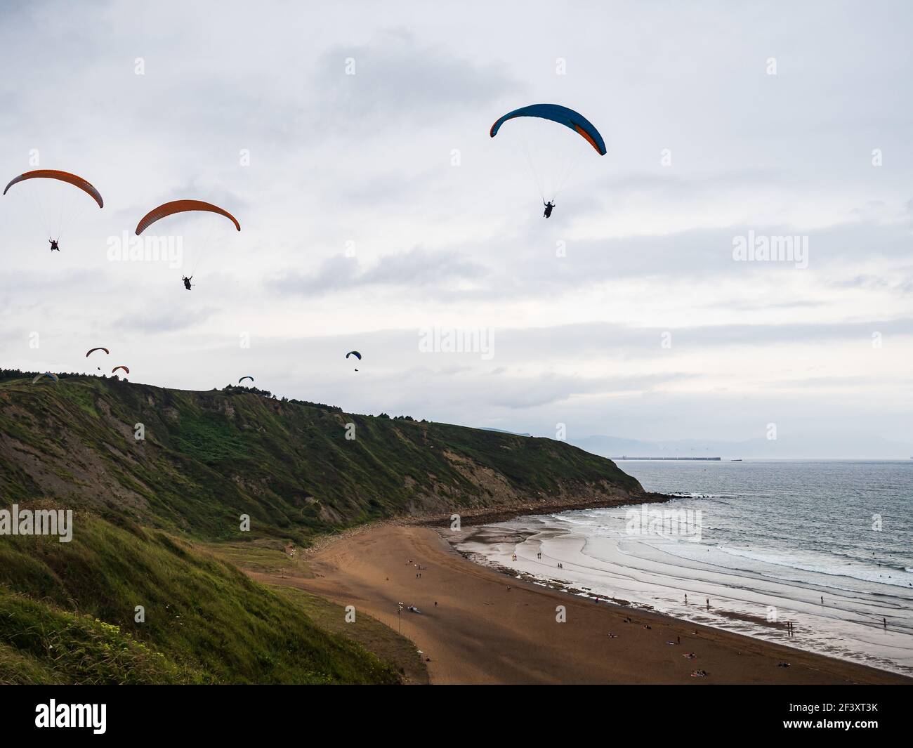 SOPELANA, SPAIN - Mar 17, 2021: several people paragliding over the cliffs of blowna beach Stock Photo