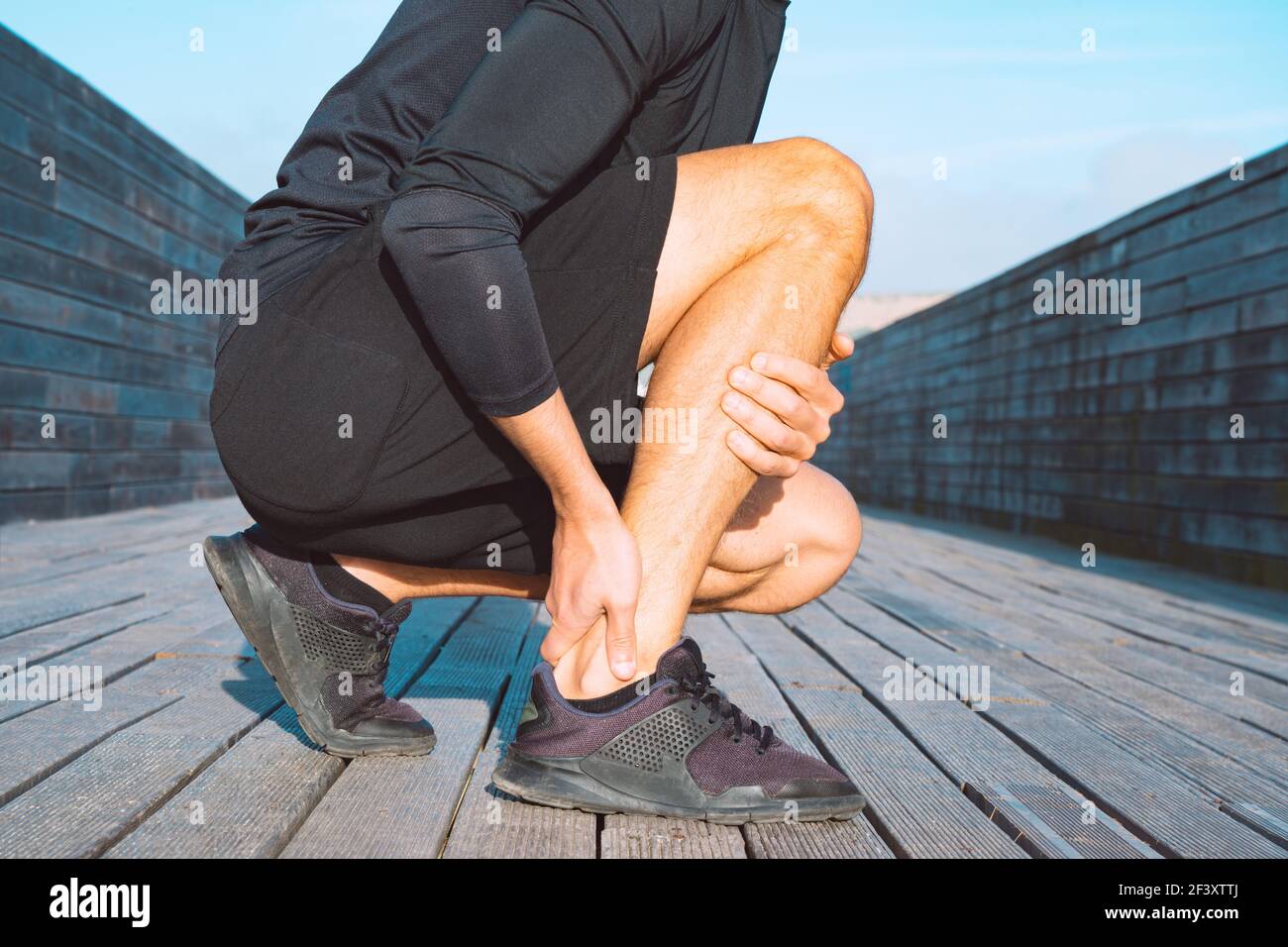 Running injuries. Runner suffering from ankle pain or achilles injury. Ankle twist sprain accident Stock Photo