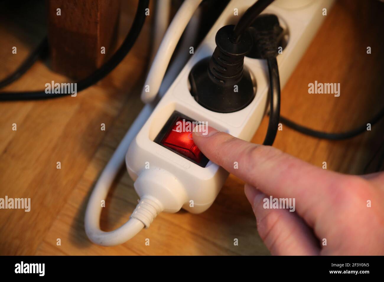 A finger pressing the red button of multiple plug extension cord Stock Photo Alamy