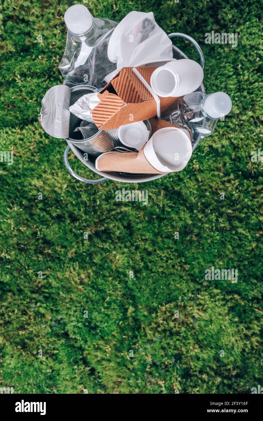 Plastic waste, food packaging in trash bin trash collection on green