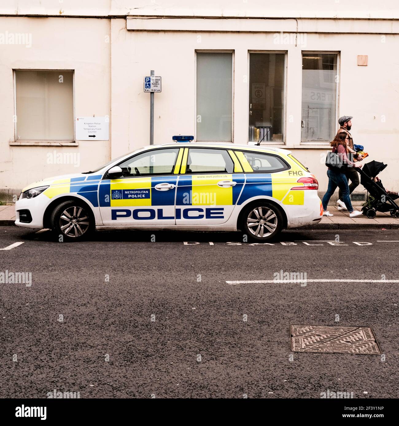 London UK, March 18 2021, Young Couple Pushing A Baby Pushchair Past A Parked Police Patrol Car Stock Photo