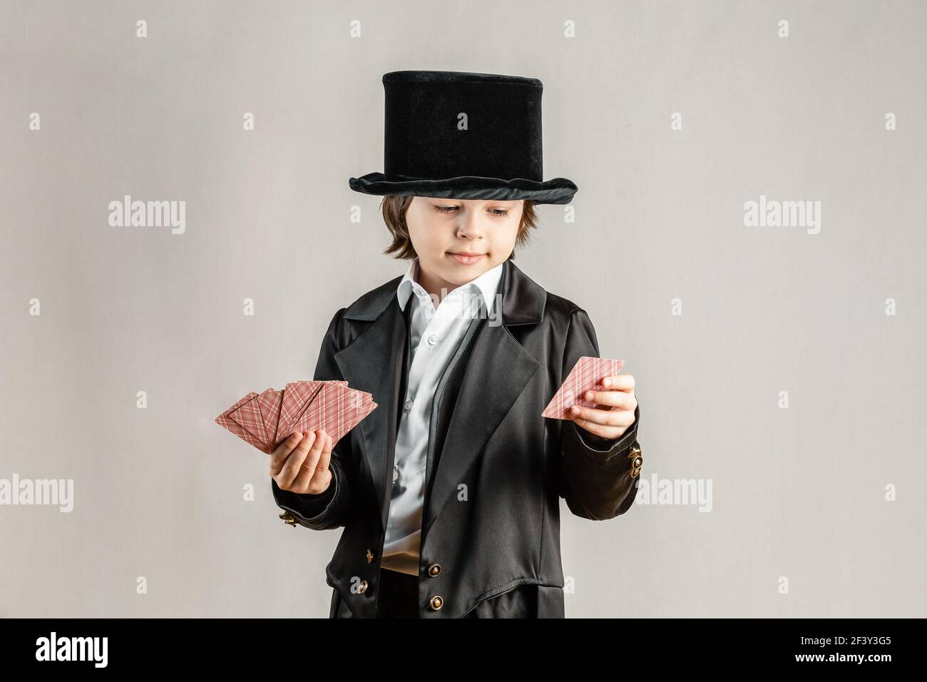 Young six year old boy wearing black suit and showing playing cards