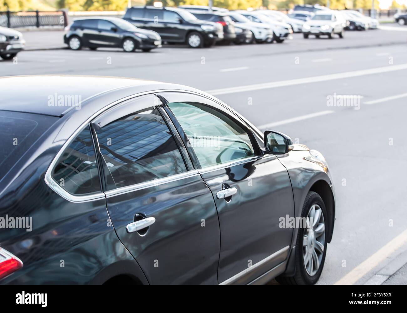 Car moves on a multi-lane road. On the opposite side of the road several cars are parked. Stock Photo