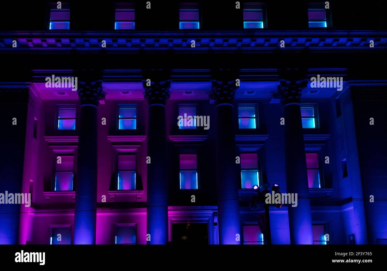 Four-story building with columns illuminated at night with purple and blue for a winter festival Stock Photo