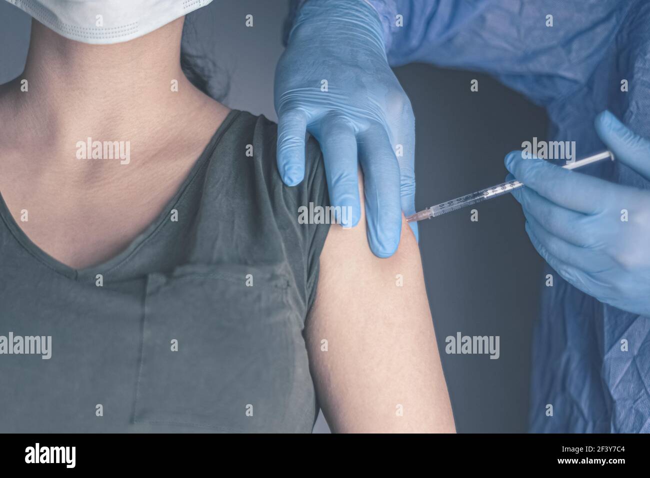 Coronavirus vaccine concept and background. Woman in medical face mask getting Covid-19 vaccine. Stock Photo
