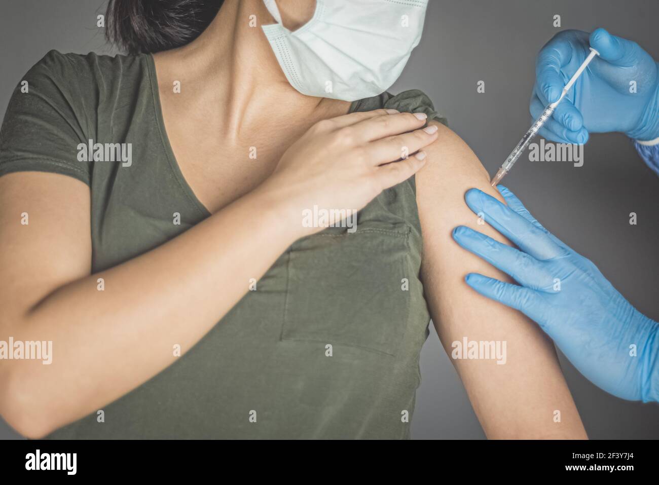 Coronavirus vaccine concept and background. Woman in medical face mask getting Covid-19 vaccine. Stock Photo