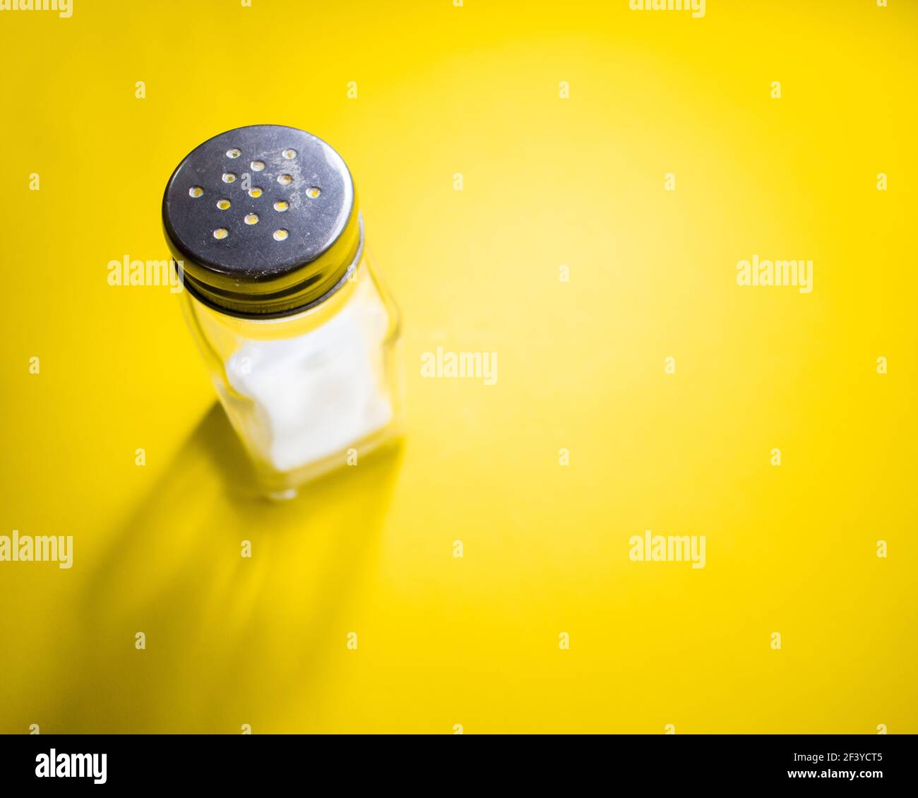 A high angle shot of a salt shaker on a yellow surface Stock Photo Alamy