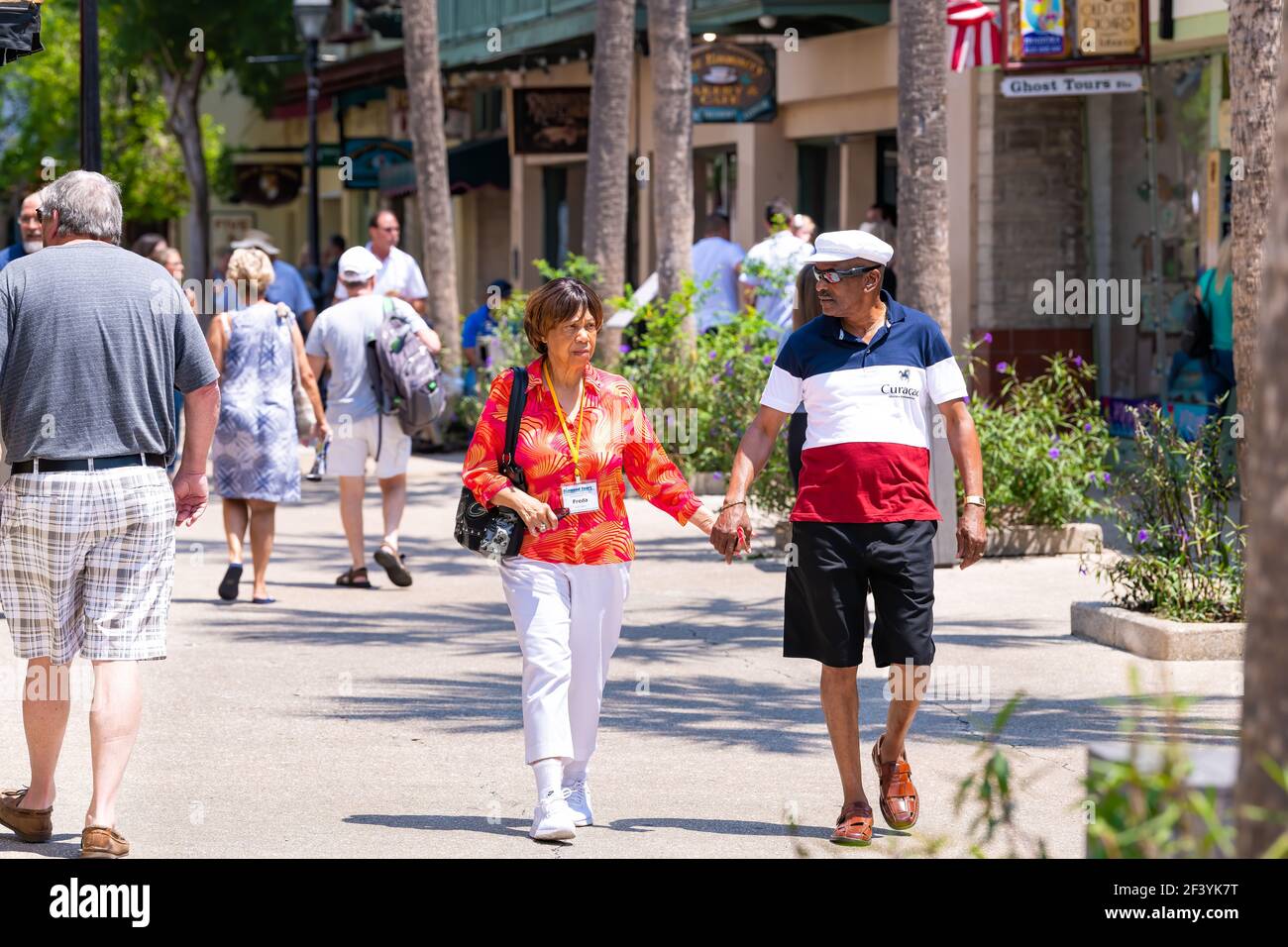 St. Augustine, USA - May 10, 2018: St George Street with senior couple people holding hands walking by stores shops and restaurants in downtown old to Stock Photo