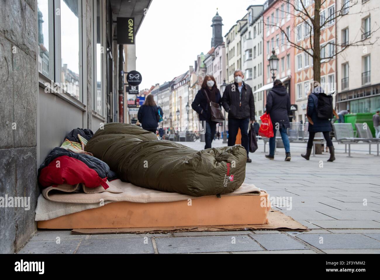 Passant*innen gehen an einem Obdachlosen im Schlafsack vorbei. Während die Inzidenz in München weiter ansteigt und evtl. bald die Geschäfte wieder schließen müssen, sind viele Menschen am 18. März 2021 in der Münchner Innenstadt unterwegs und kaufen ein. Die neuen Varianten des Coronavirus betragen in der Landeshauptstadt aktuell fast 70%. * While the incidence is rising and the shops may have to close again, many people on March 18 2021 go to the pedestrian zone in Munich, Germany and buy stuff. The number of new variants in Munich is about 70%. (Photo by Alexander Pohl/Sipa USA) Stock Photo