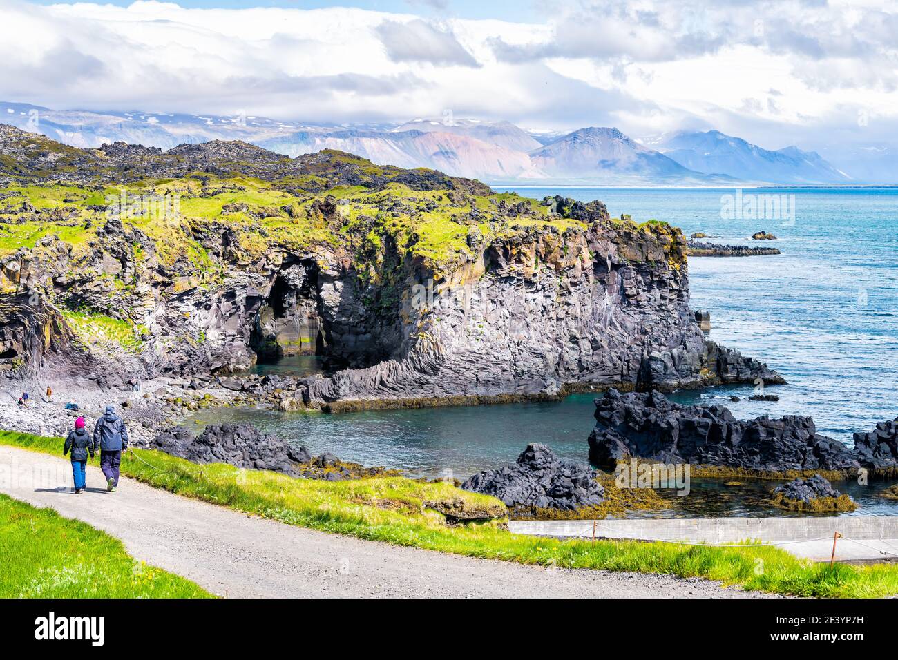 Snaefellsjokull, Iceland - June 18, 2018: Rocky formation in Hellnar National park Snaefellsnes Peninsula with ocean and cave cove people tourists on Stock Photo