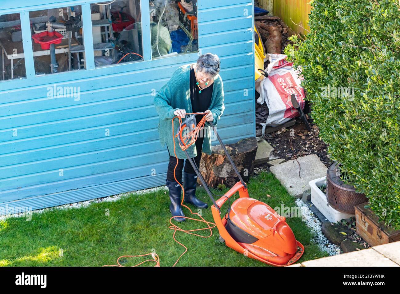 middle aged woman cutting the grass with a lawnmower Stock Photo