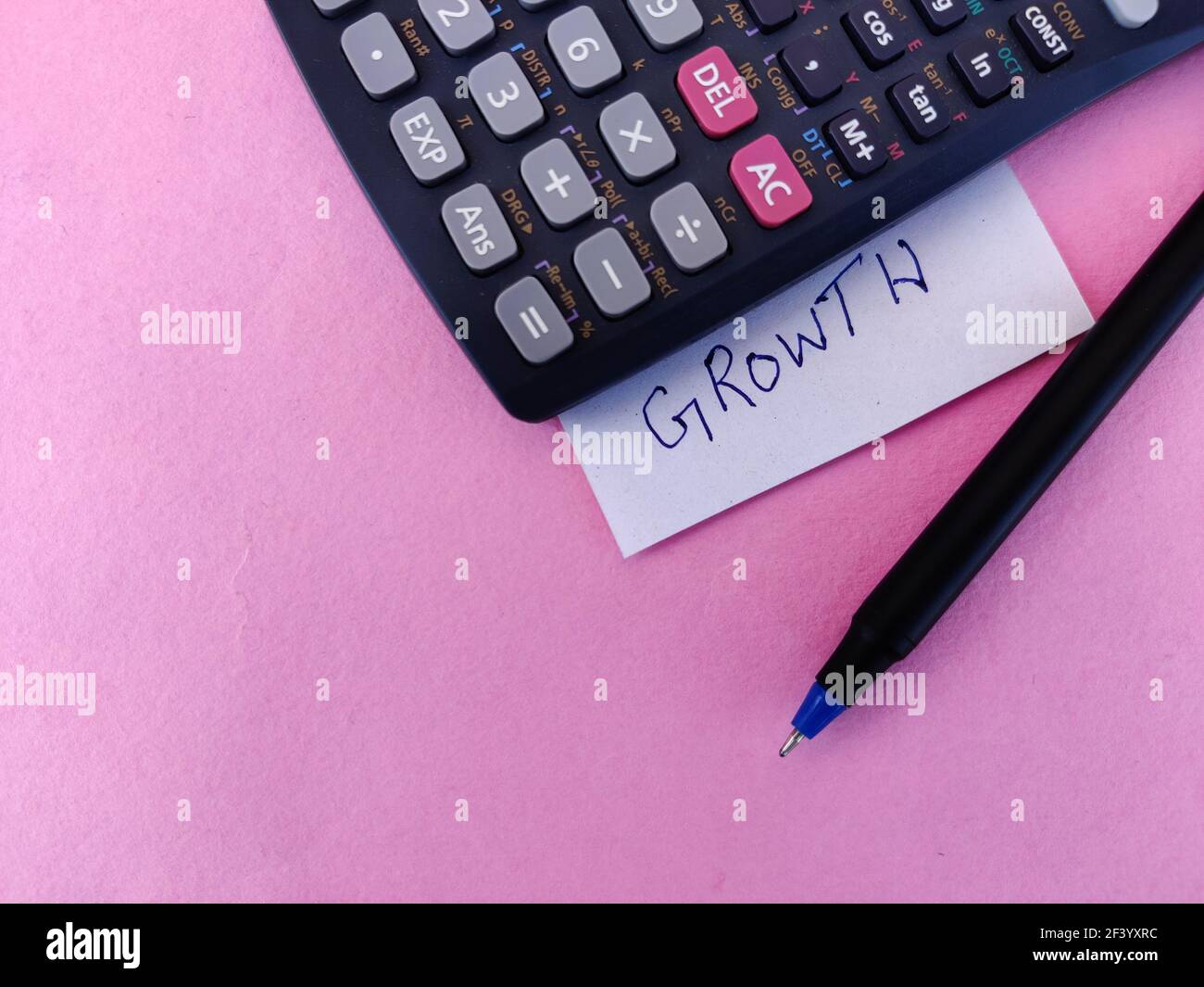 A White sticky note with text GROWTH kept under scientific calculator ...