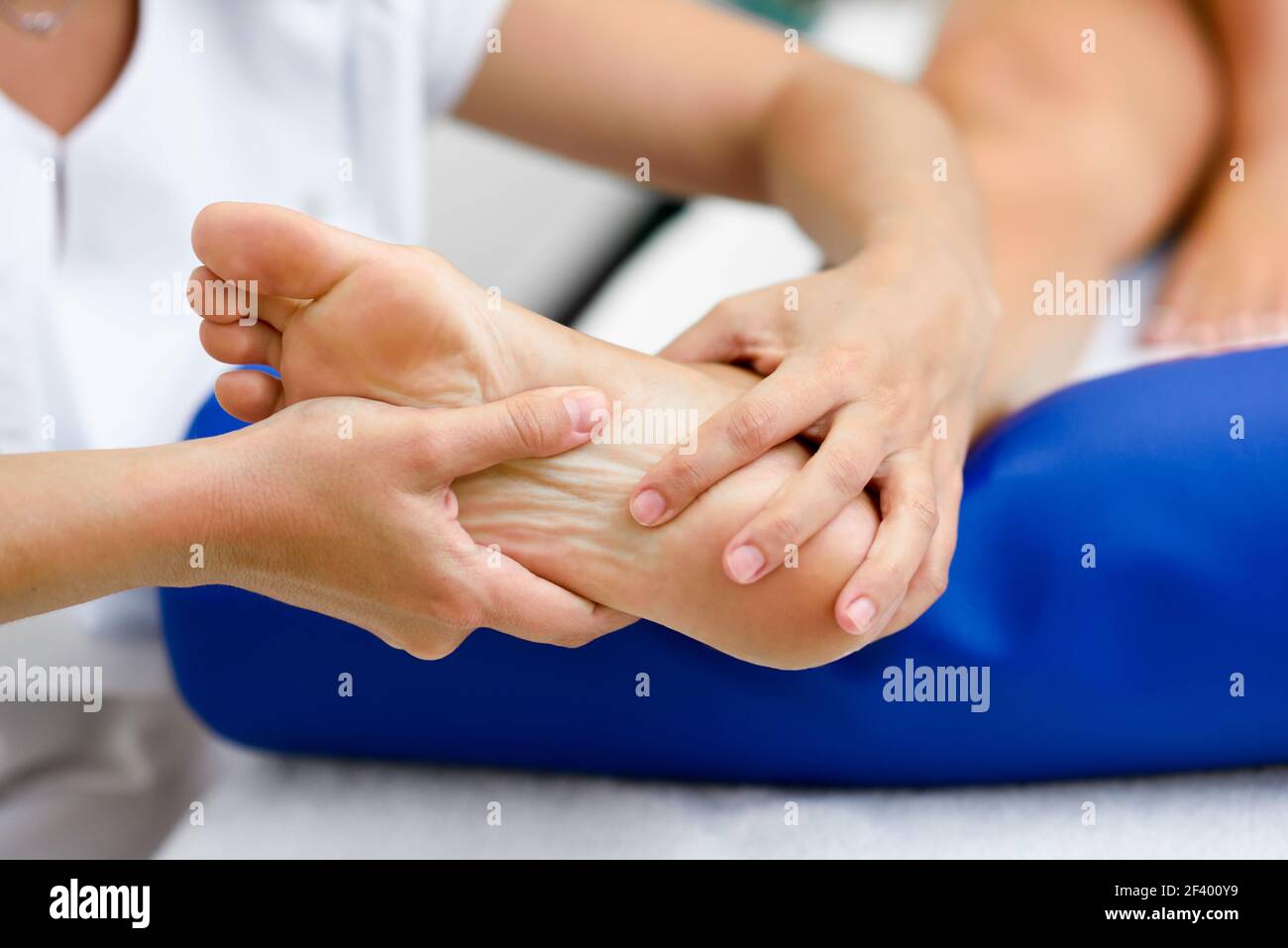 Medical massage at the foot in a physiotherapy center. Female physiotherapist inspecting her patient. Stock Photo