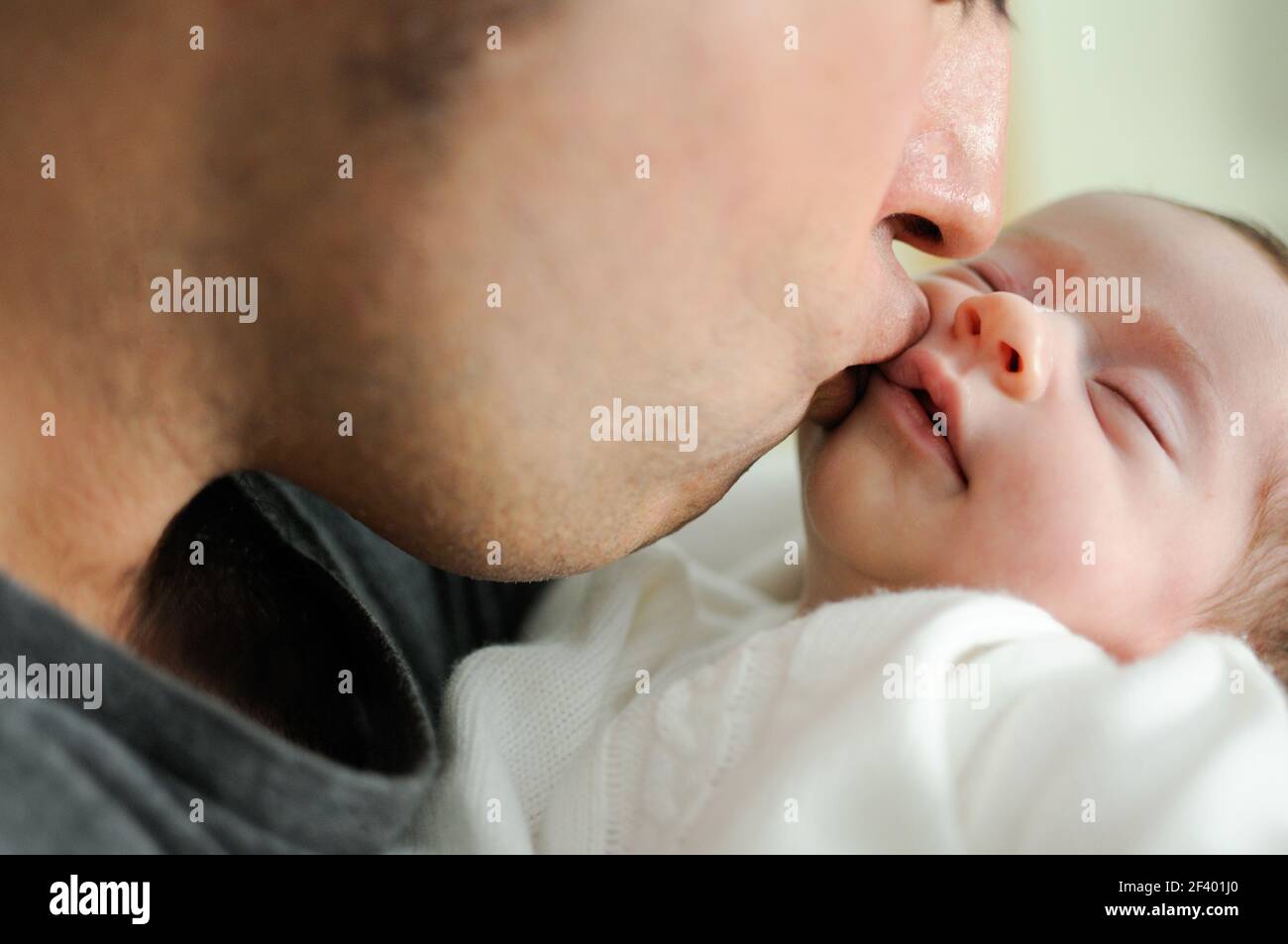 Father kissing his newborn baby girl.. Father kissing his newborn baby girl. Close-up portrait Stock Photo