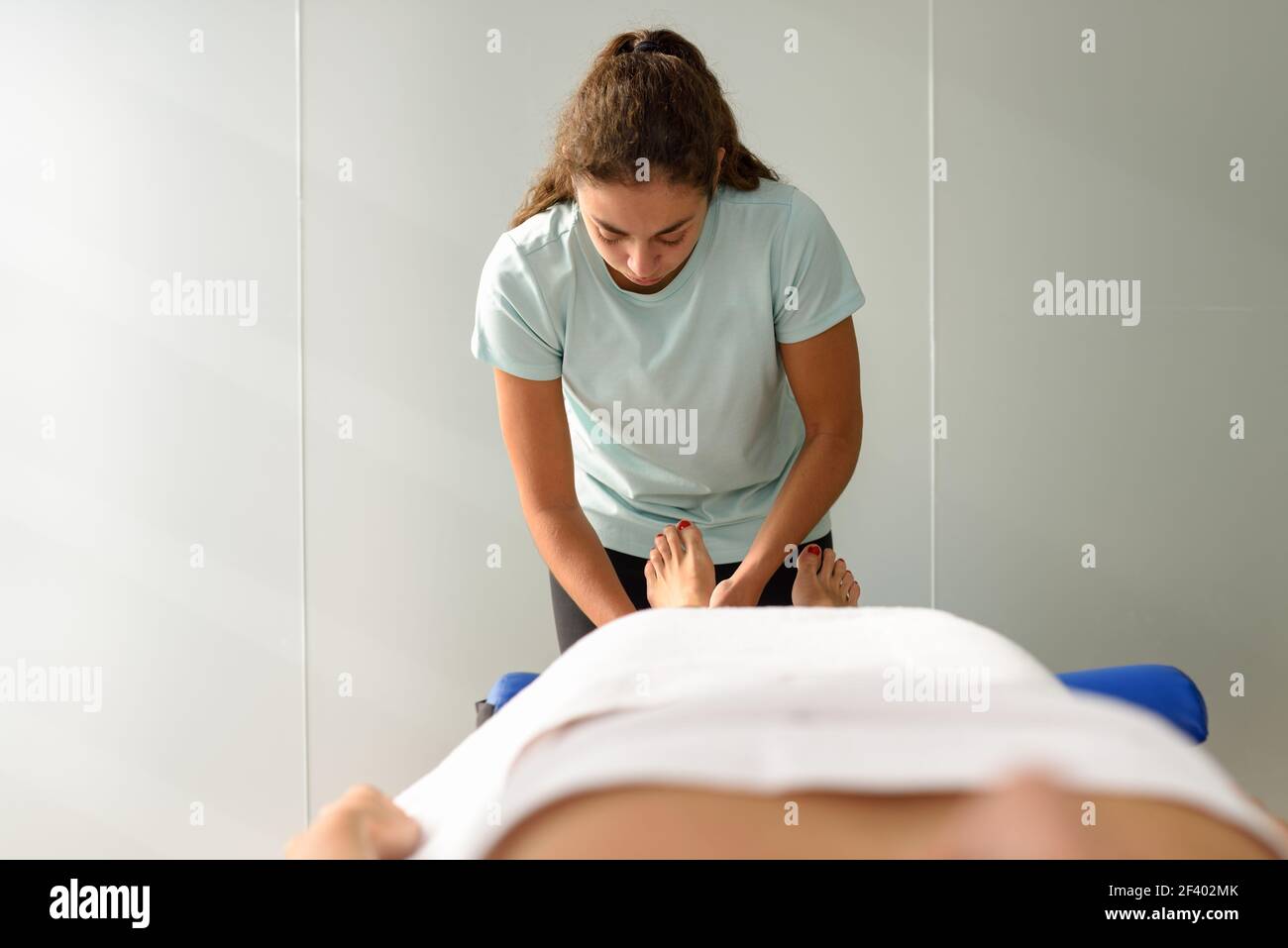 Medical massage at the foot in a physiotherapy center. Female physiotherapist inspecting her patient. Stock Photo