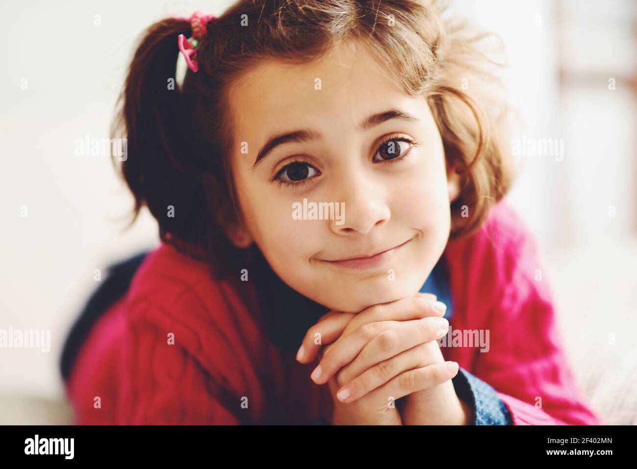 Adorable little girl with sweet smile lying down on bed. Closeup