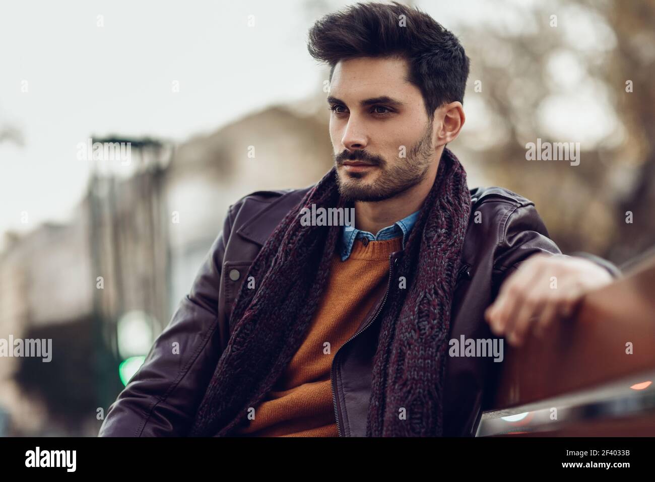 Thoughtful young man sitting on an urban bench. Attractive guy with ...