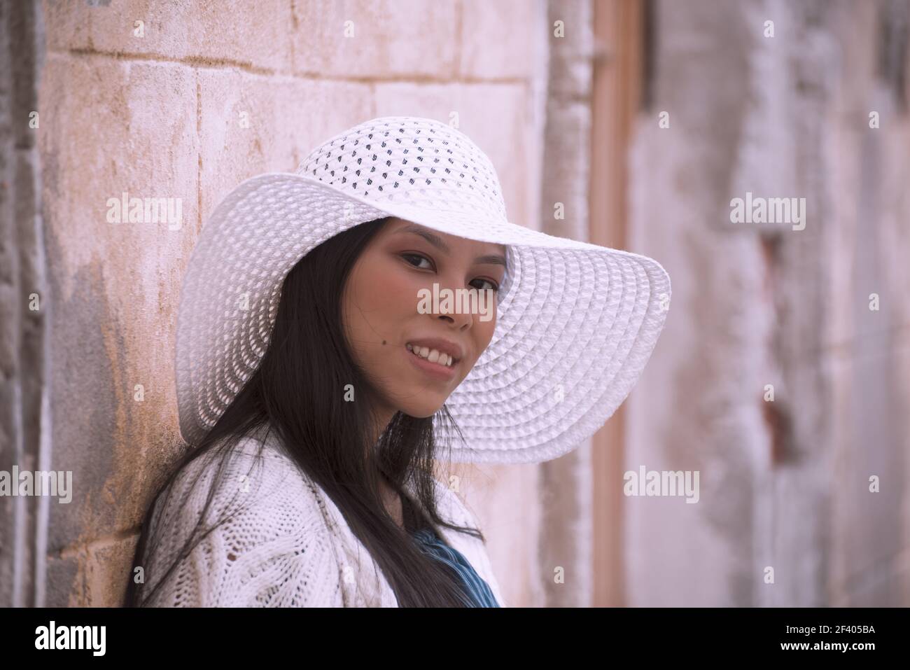 Young asian pregnant woman in white hat near old building Stock Photo