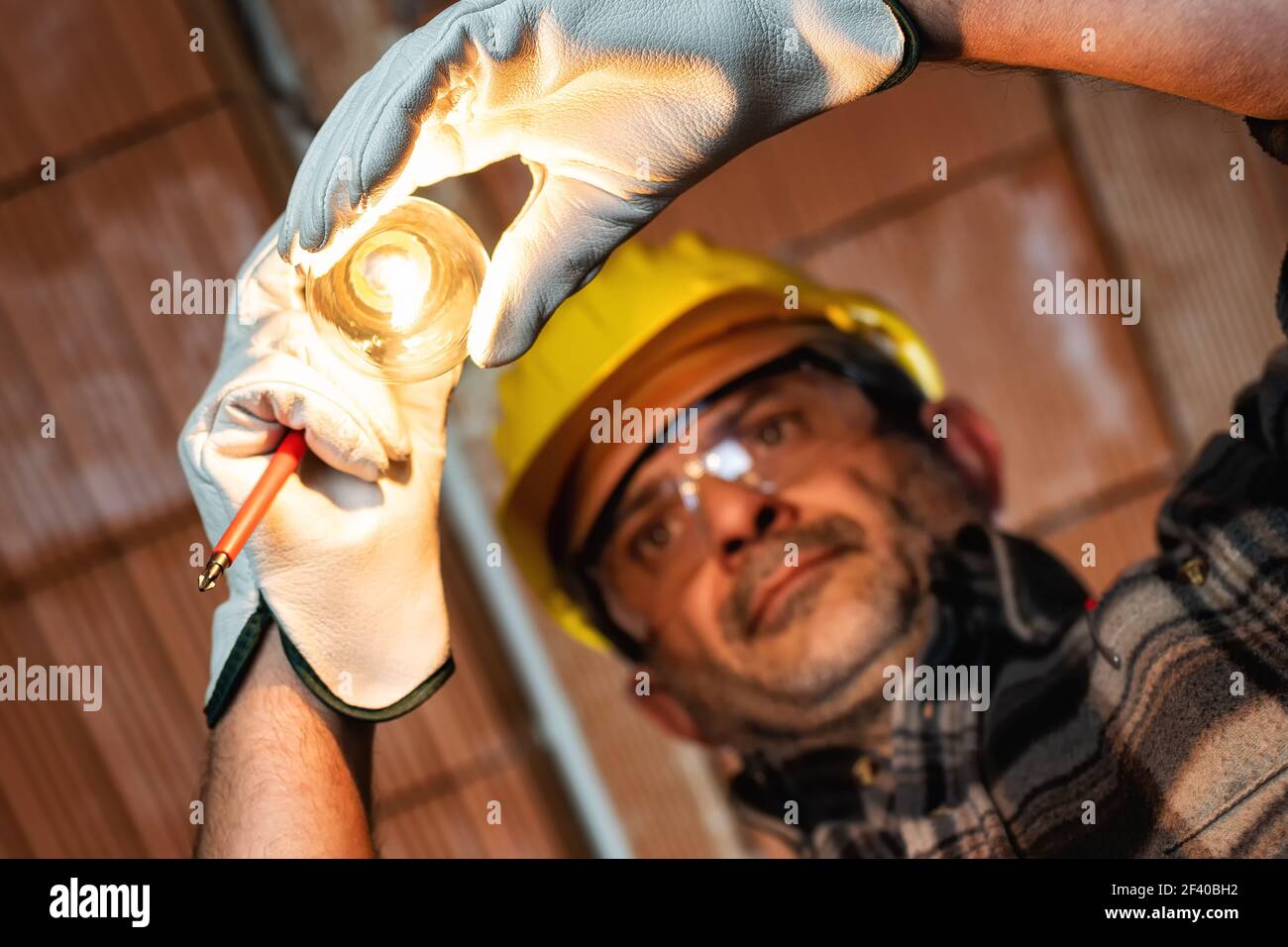 Electrician worker at work replaces the light bulb in a residential