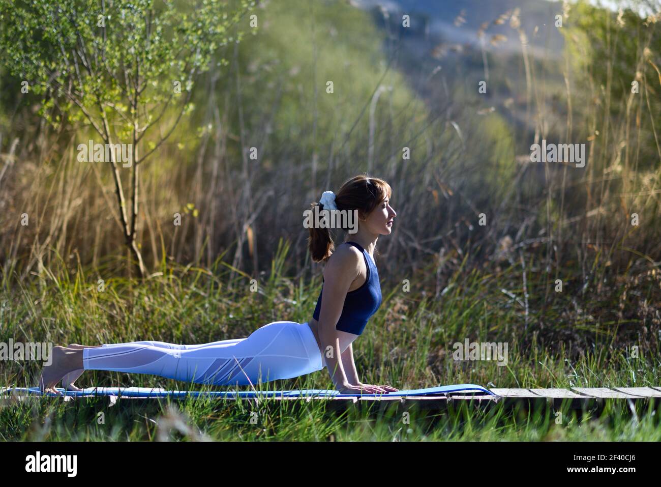 Young woman doing yoga in nature. Female wearing sport clothes. Stock Photo