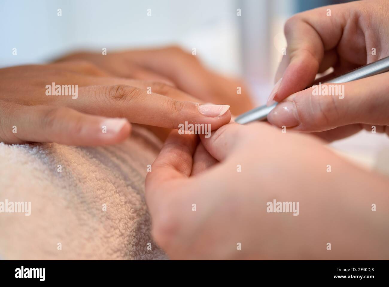 Woman with deteriorated nails in a salon receiving a manicure by a beautician with nail file. Stock Photo
