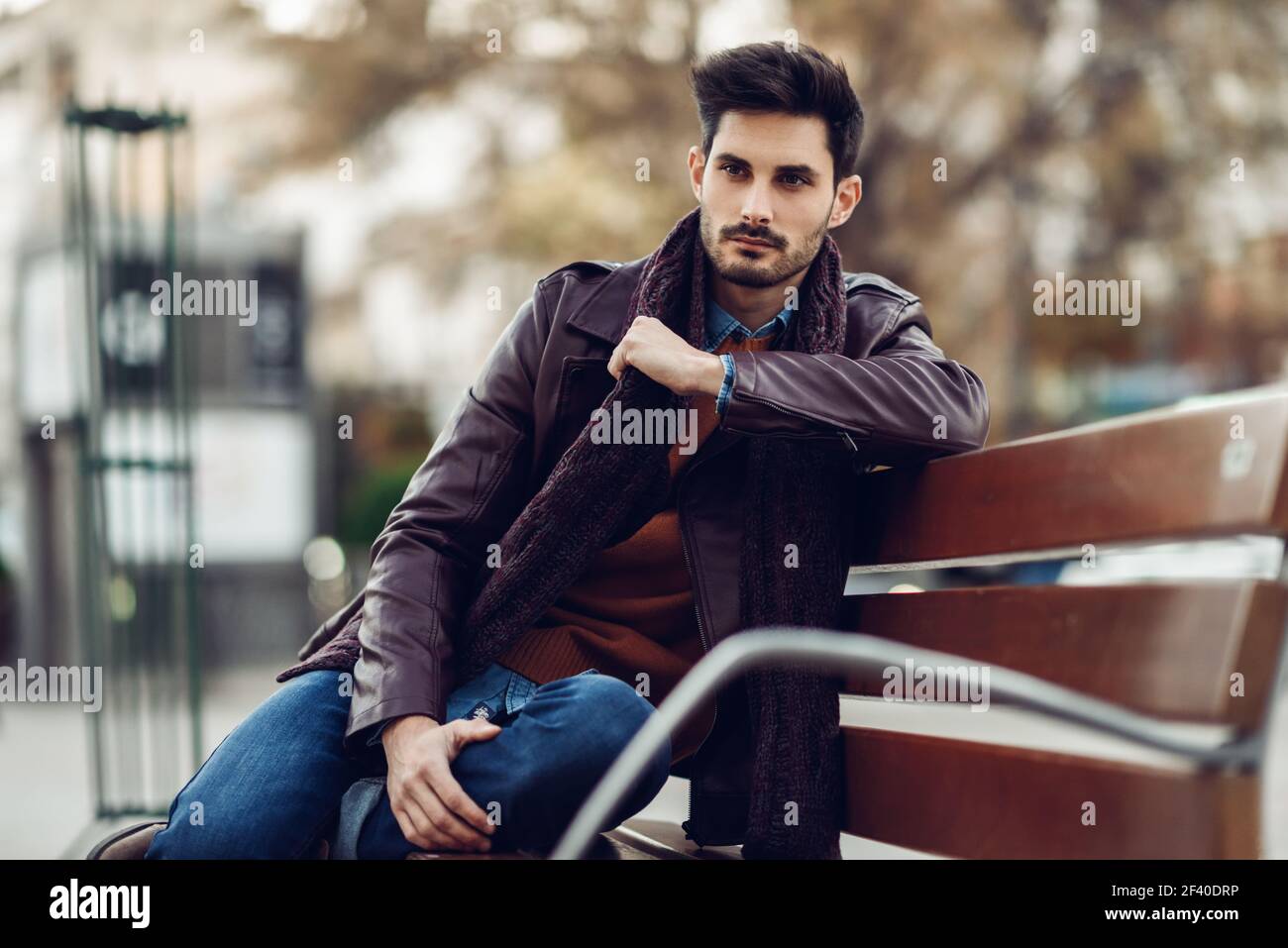 Thoughtful young man sitting on an urban bench. Attractive guy with ...