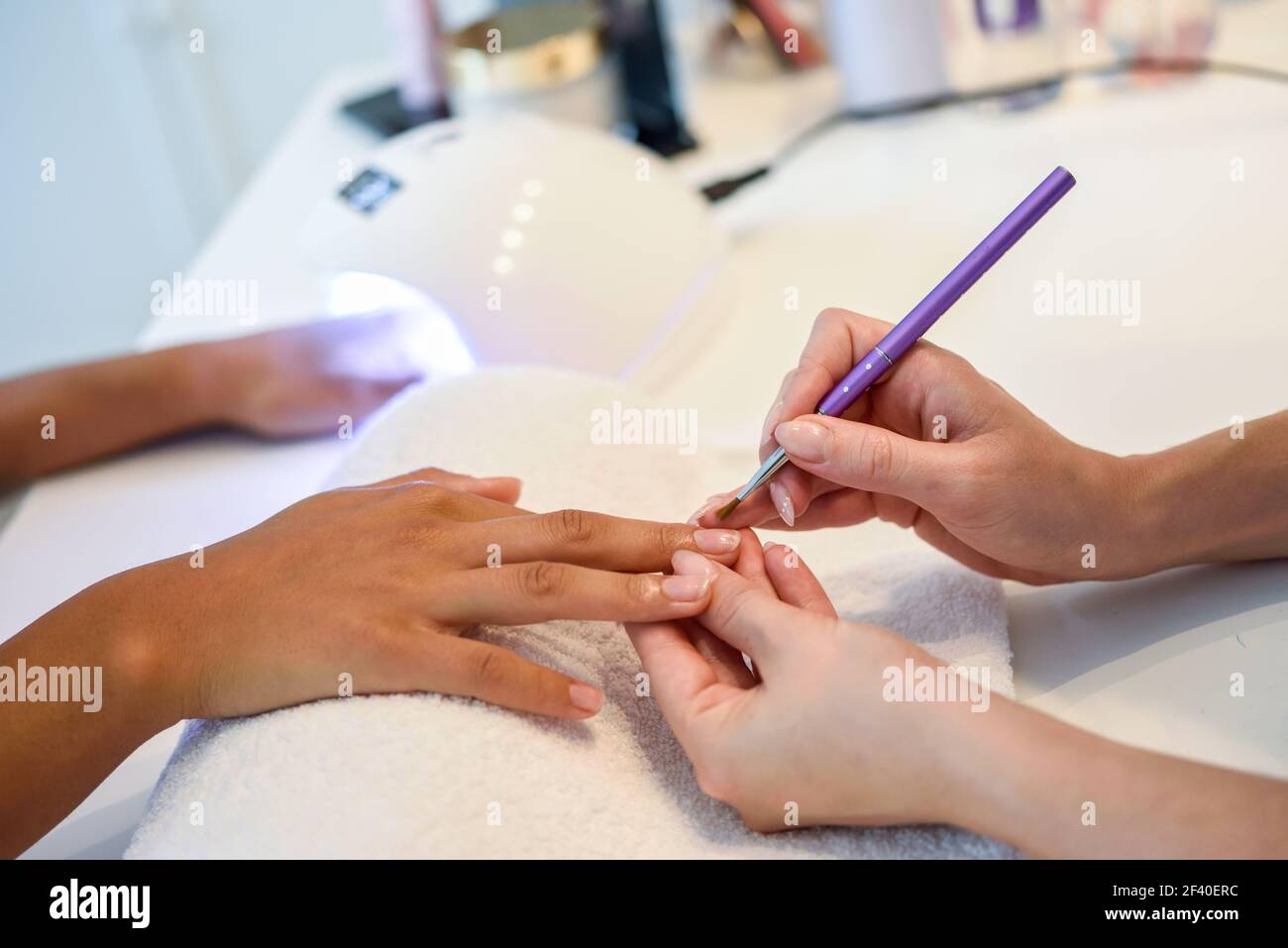 Close-up of beautician painting a woman&rsquo;s nails with a brush in a nail salon. Costumer receiving a manicure. Stock Photo