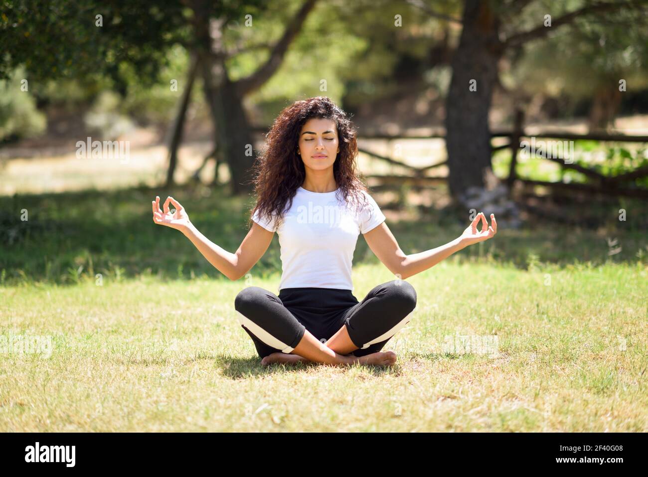 Young woman doing yoga in nature. Lotus figure. - a Royalty Free