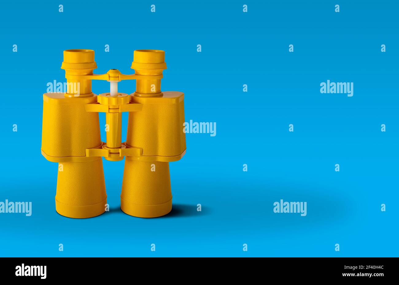 Yellow binoculars isolated on blue background Stock Photo