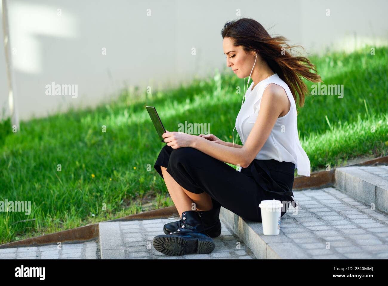 Young businesswoman working with her laptop computer sitting on urban steps outdoors.. Middle-age businesswoman working with her laptop computer sitting on the floor. Stock Photo