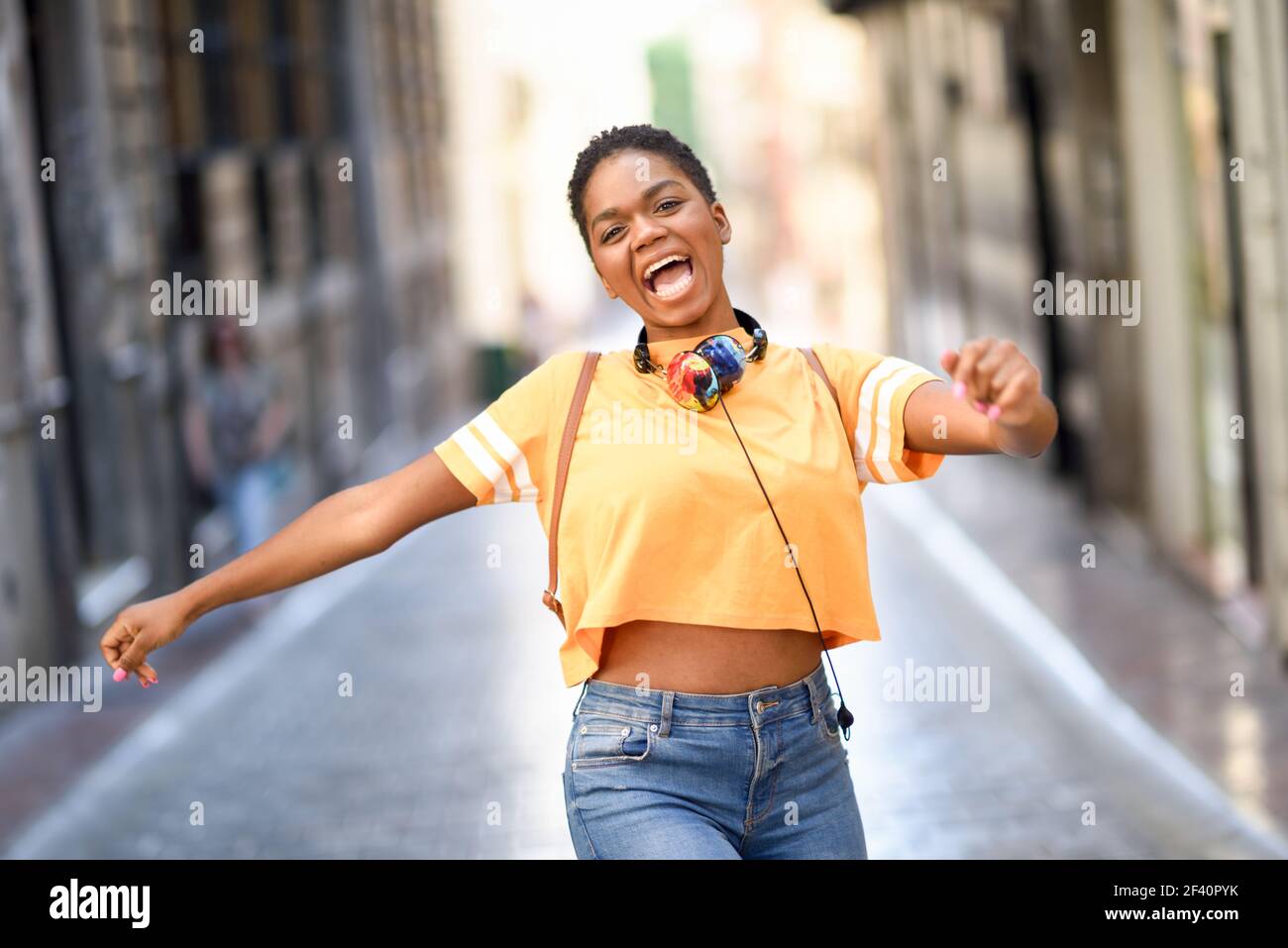 Young black woman is dancing on the street in Summer. Girl traveling alone. Lifestyle concept.. Young black woman is dancing on the street in Summer. Girl traveling alone. Stock Photo