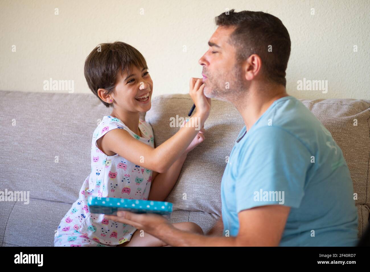Little cute daughter doing make-up to her father. Dad spending free time with her daughter. Alternative masculinity concept.. Little cute daughter doing make-up to her father Stock Photo