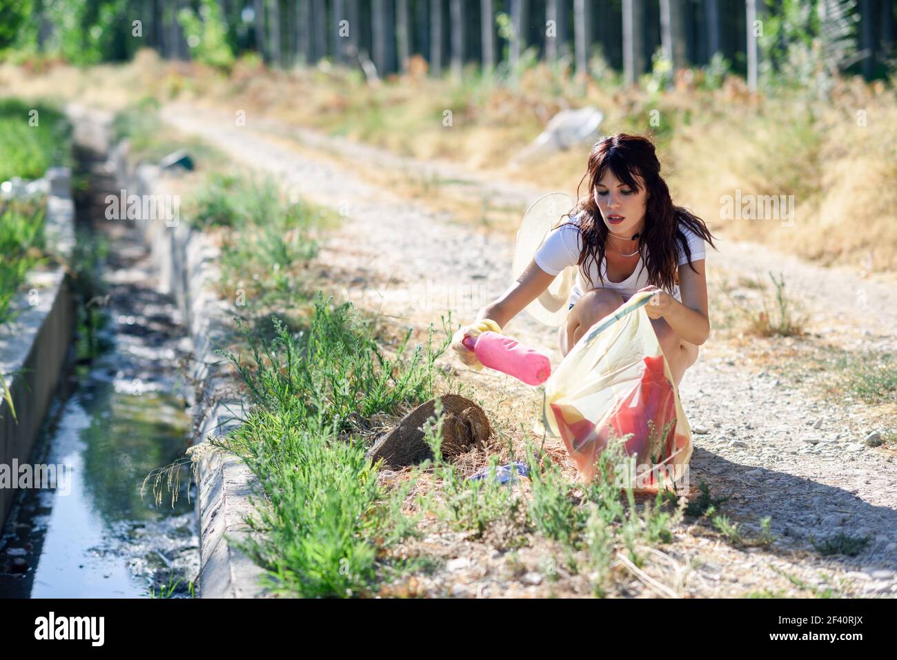 Young woman hand collecting garbage of the grass in the countryside. Woman hand collecting garbage of the grass in the countryside Stock Photo