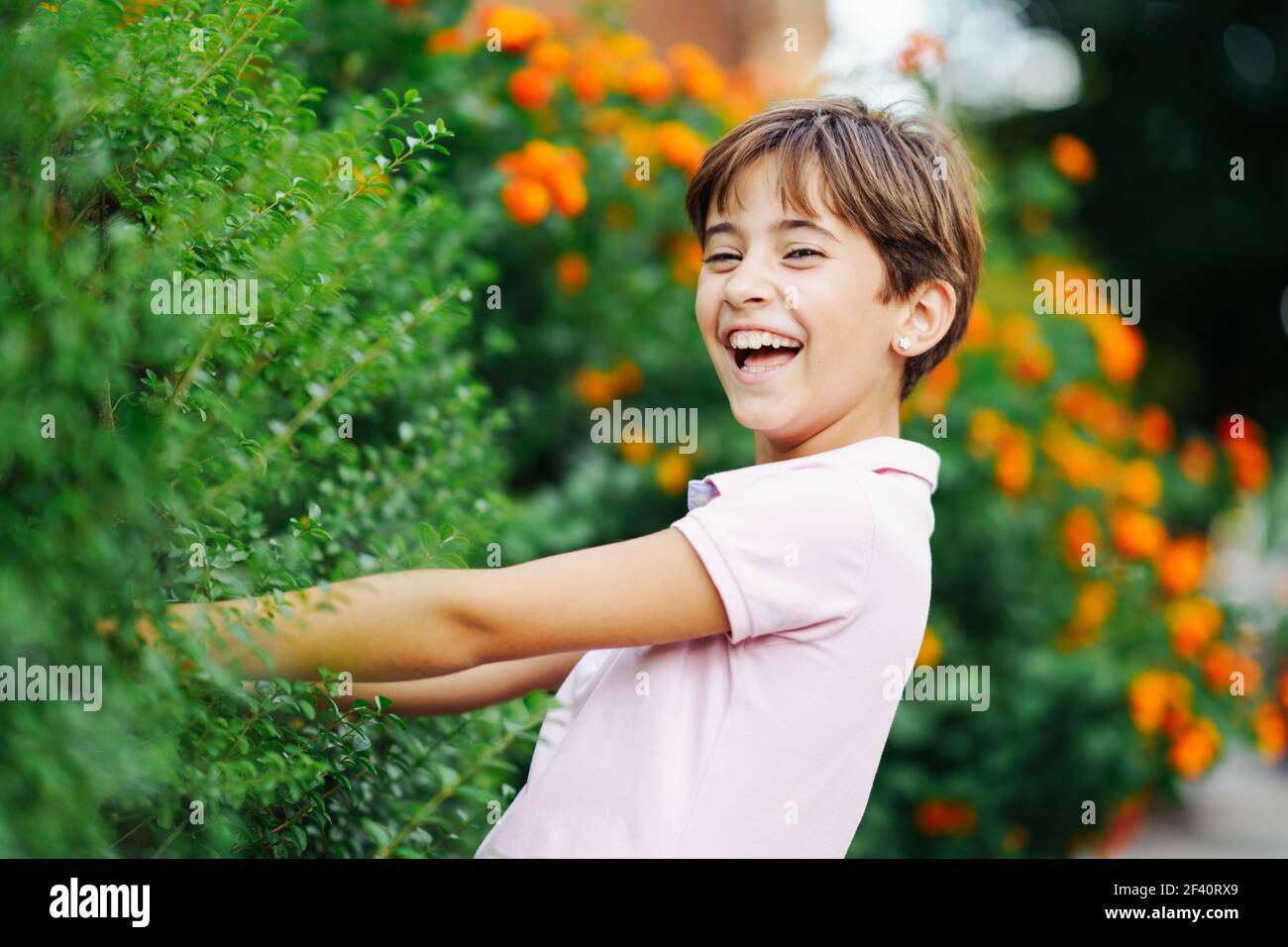 Little girl with very short hair, laughing in an urban park wearing