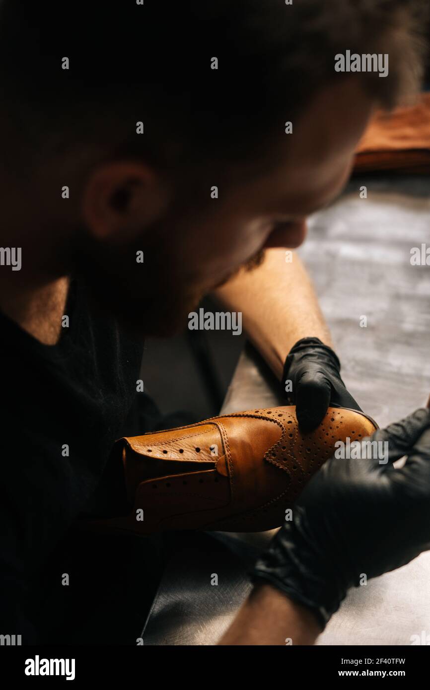 Top view of shoemaker wearing black latex gloves cleaning old light