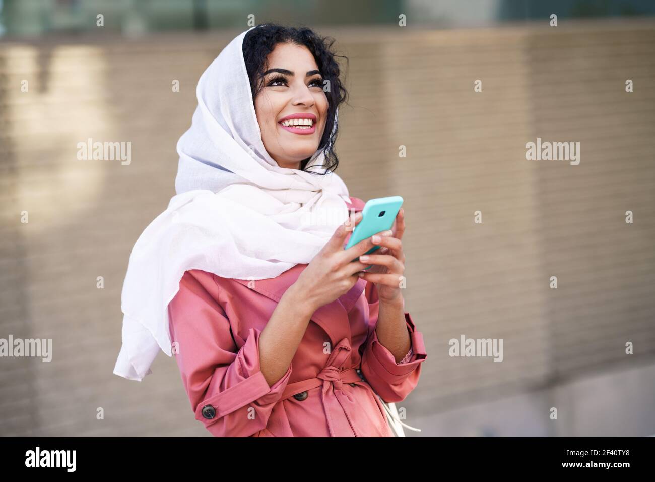 Young Muslim woman wearing hijab headscarf texting message with her ...