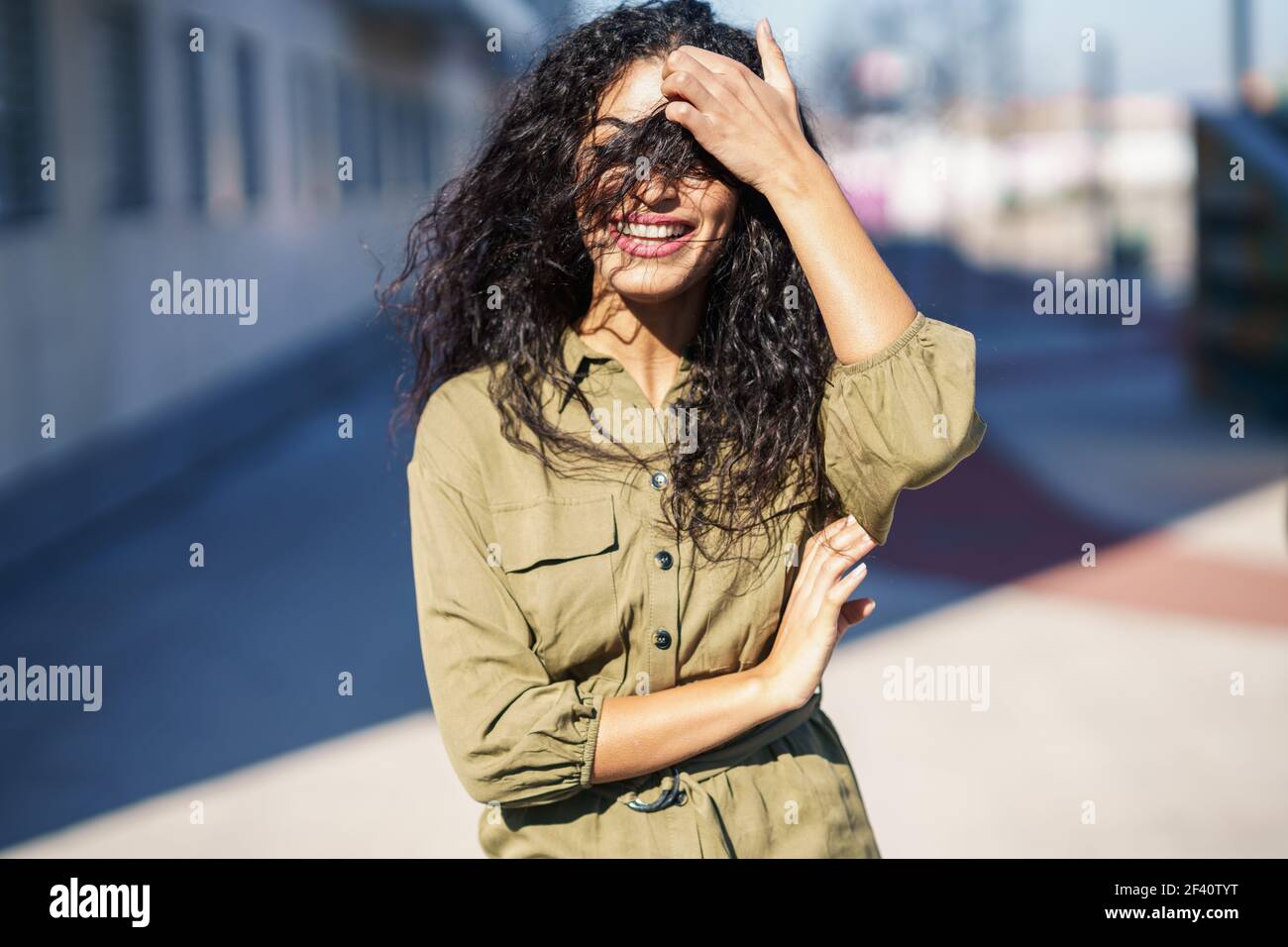 Young Arab Woman with curly hair in her face on urban yellow wall. Arab Woman with curly hair in her face Stock Photo