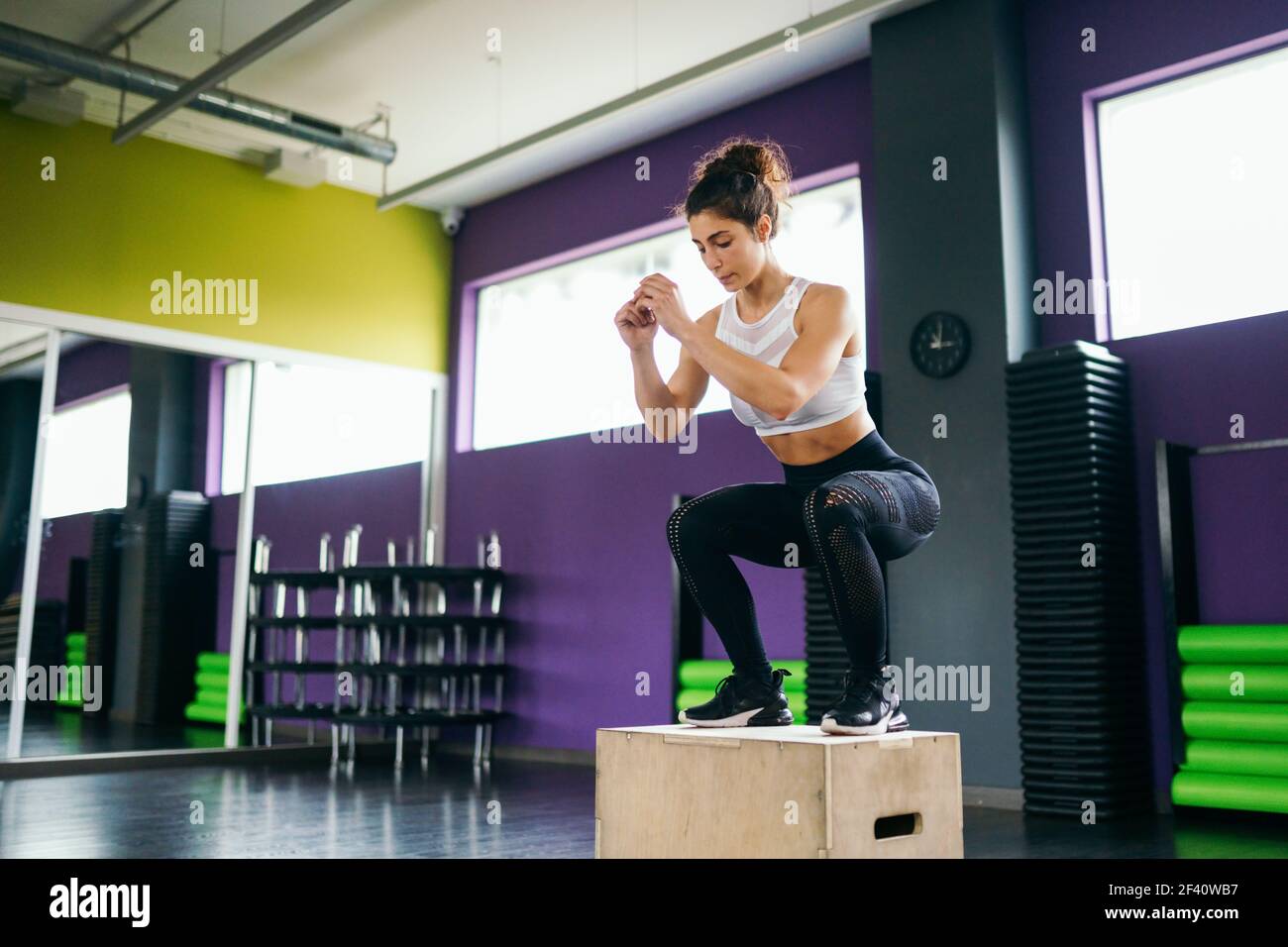 Athletic woman doing squats on box as part of exercise routine