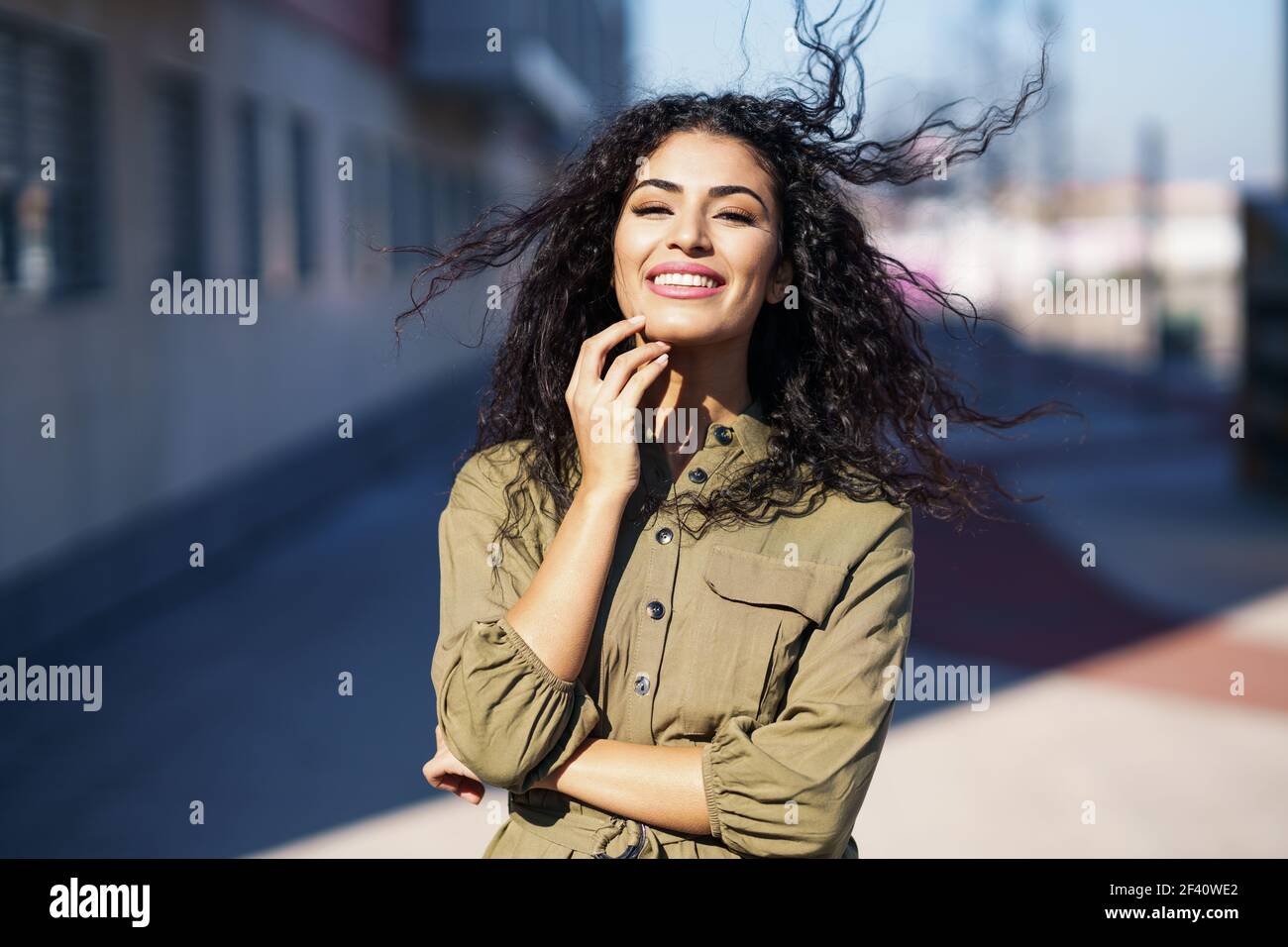 Arab woman with curly hair moved by the wind in urban background. Arab woman with curly hair moved by the wind Stock Photo