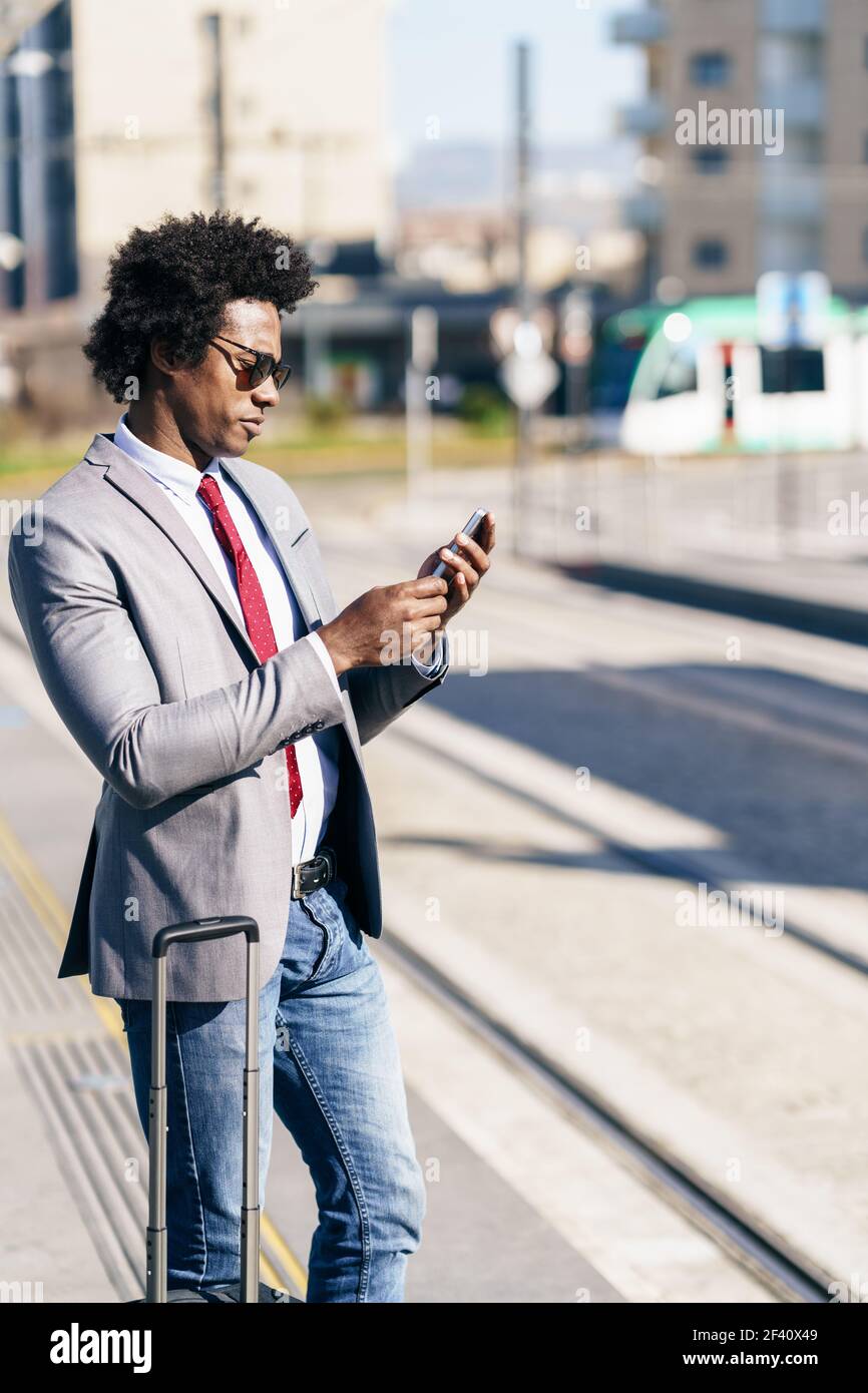 Black Businessman wearing suit waiting his train on an outdoors station