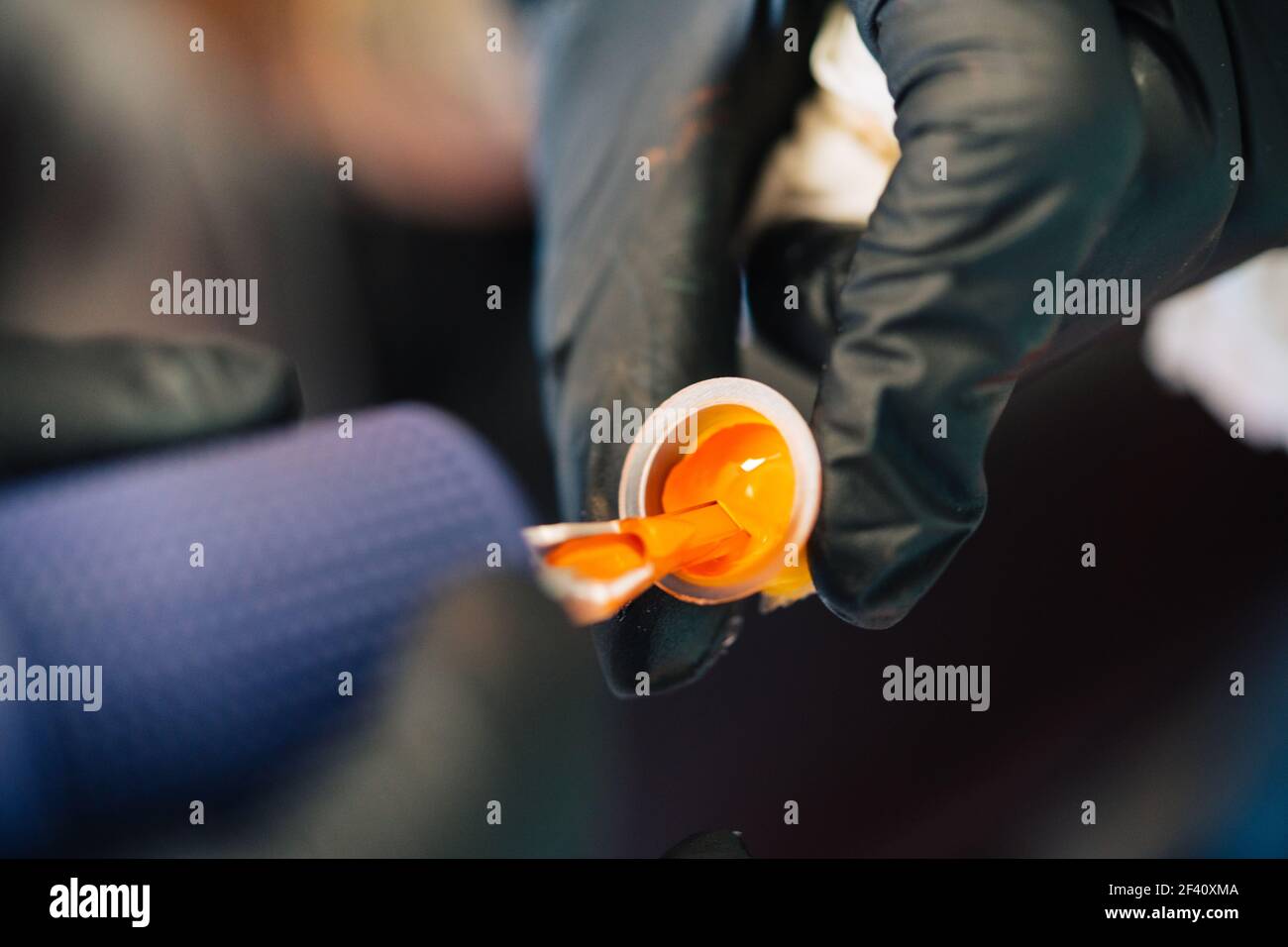 Tattoo woman loading the tattoo machine with orange ink. Tattoo concept.. Tattoo woman loading the tattoo machine with ink. Stock Photo