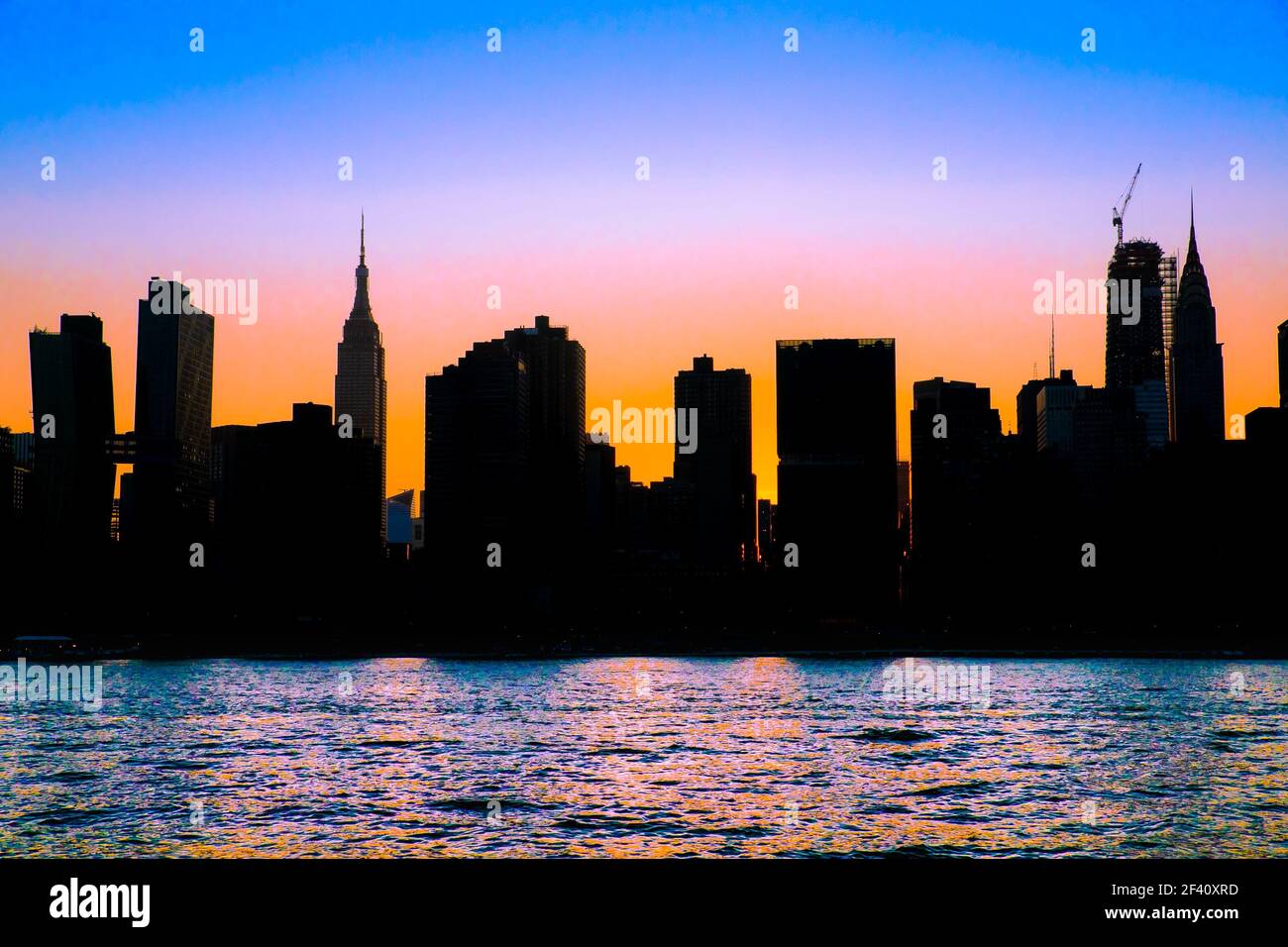 New York City skyline with silhouetted buildings and colorful sunset sky Stock Photo