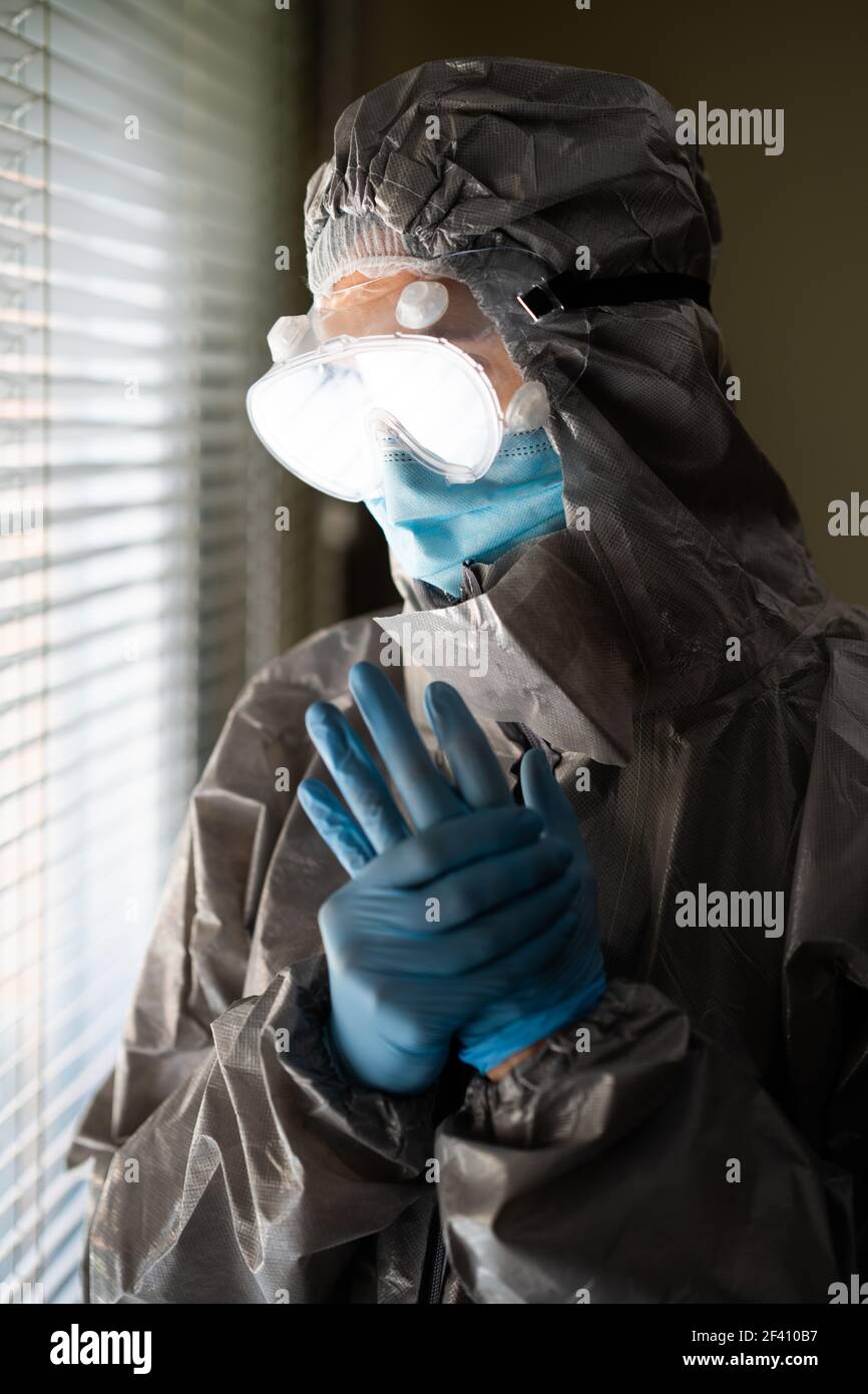 Worried Doctor or lab technician scientist in PPE Personal Protective Equipment near a hospital window. Female Doctor in PPE Personal Protective Equipment Stock Photo
