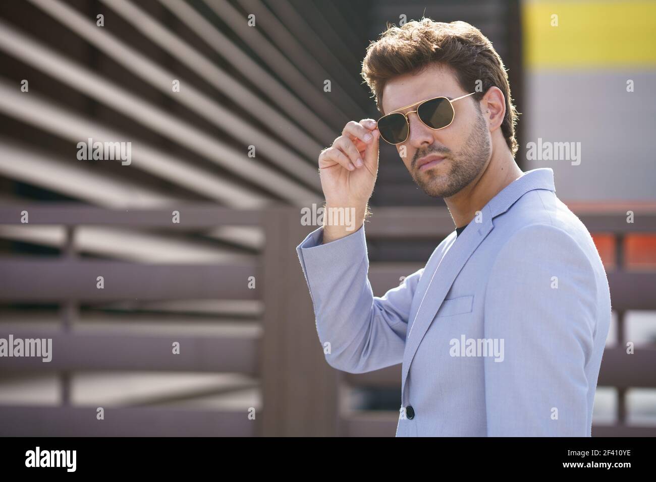 Young man, model of fashion, wearing sunglasses in urban background. Young handsome man wearing sunglasses in urban background Stock Photo